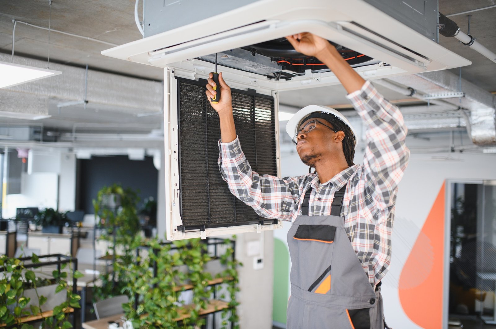Technician repairing air conditioning system in office building